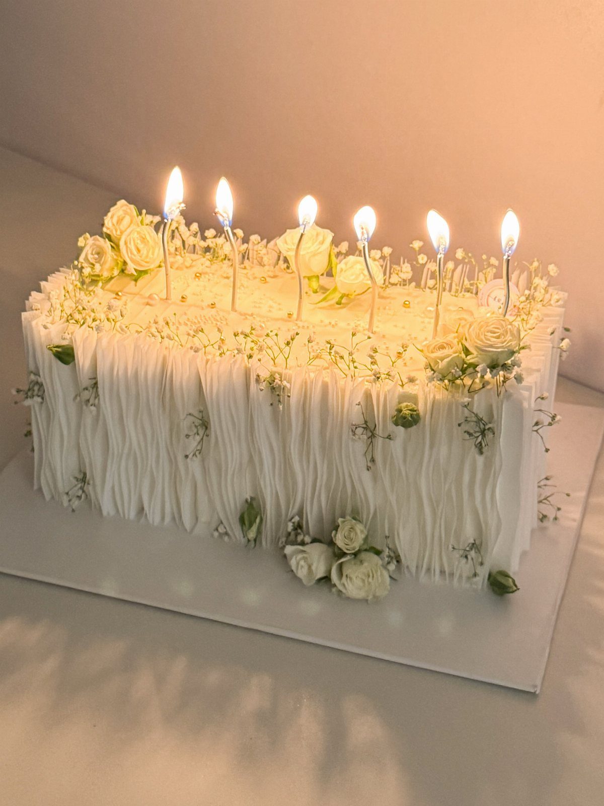 Flat Wedding Cakes: 6 Ideas for Simple, Low Tiers 5 Rectangular white frosted cake with vertical ridges, white roses, and six lit candles.