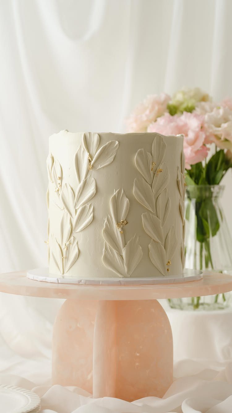 Flat Wedding Cakes: 6 Ideas for Simple, Low Tiers 1 Single-tier white wedding cake with buttercream leaves on a pink marble stand.