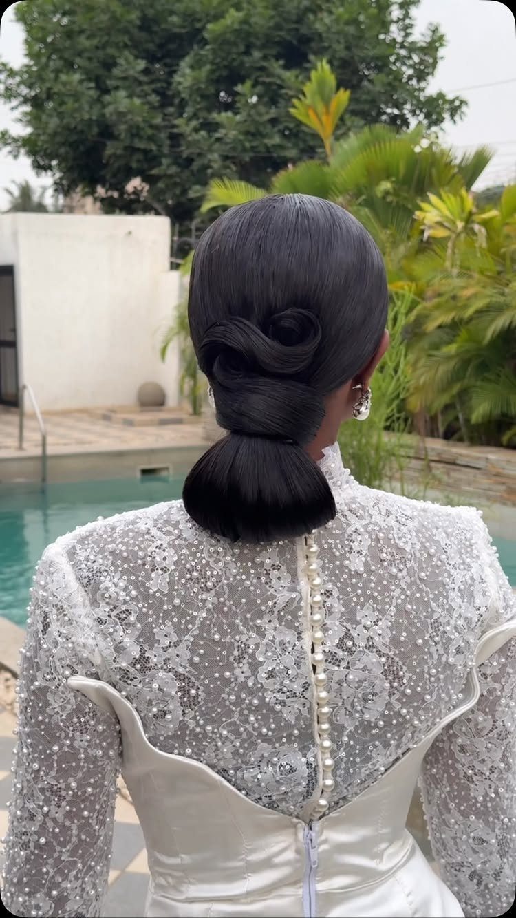 Woman from behind in a pearl-embellished white wedding dress with a sleek updo.