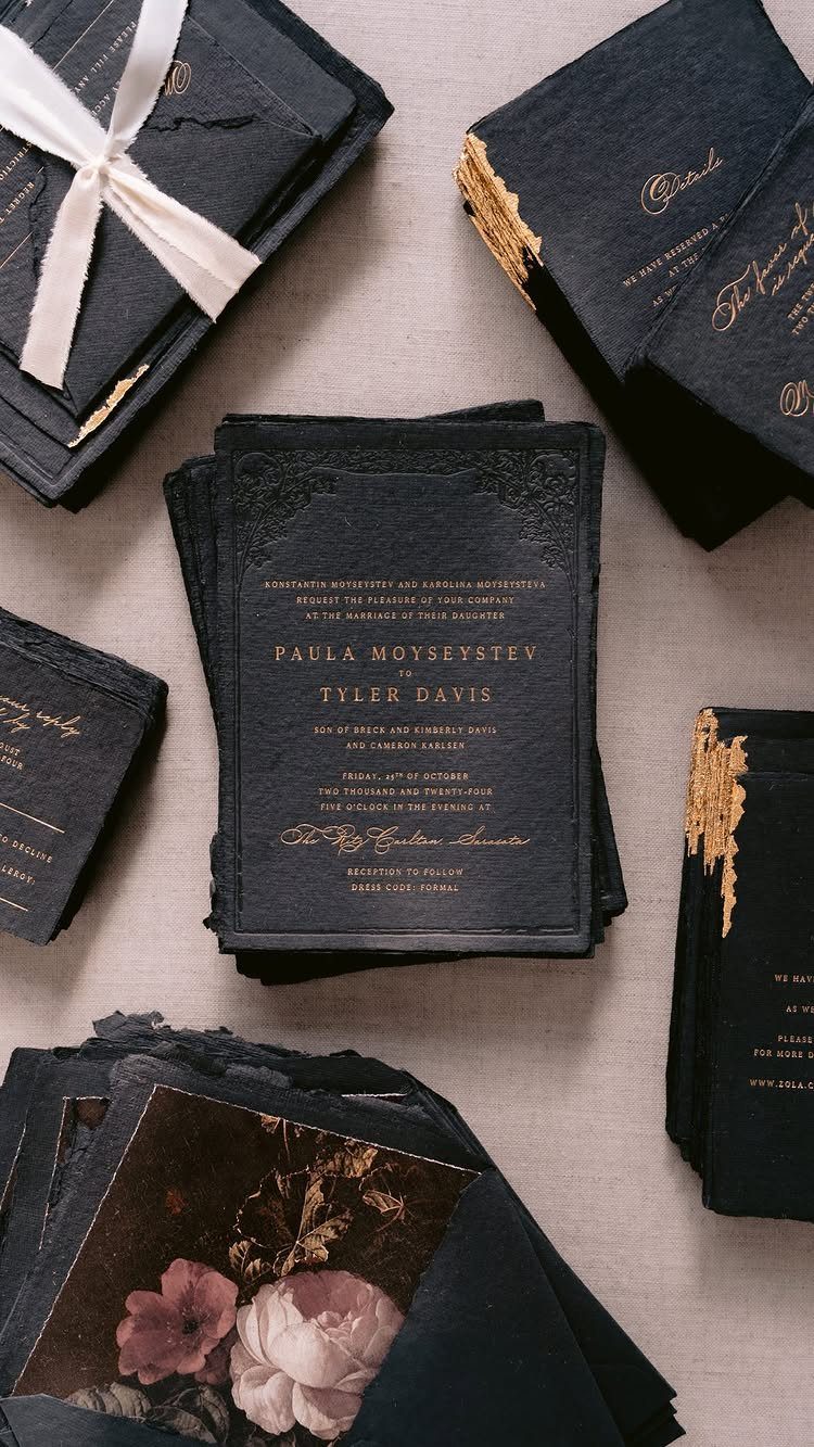8 Gothic Romance Wedding Ideas for a Dark, Moody Day 7 Black gothic wedding invitations with gold calligraphy and pink floral accents on fabric.
