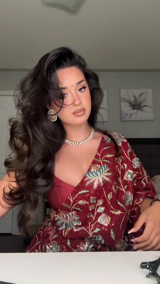 14 Ideas for Hair for a Wedding Guest, From Buns to Waves 13 Woman with voluminous bouncy blowdry curls wearing a red embroidered saree and pearls.