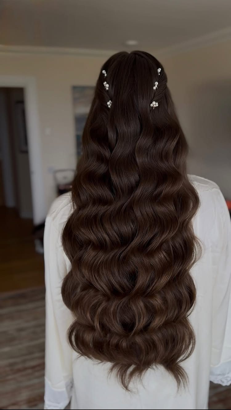 14 Ideas for Hair for a Wedding Guest, From Buns to Waves 8 Long dark brown hair styled in voluminous waves with small white floral pins.
