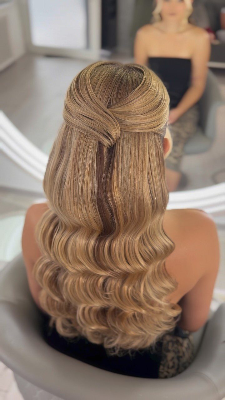 Blonde hair in a half-updo with sleek, uniform Hollywood waves and twisted top.