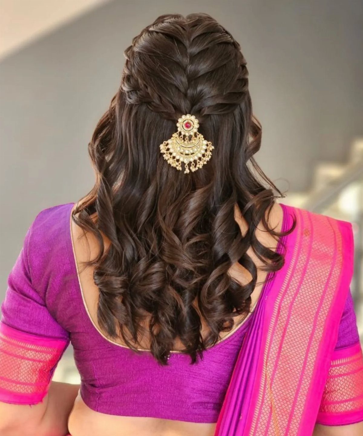 Half-updo hairstyle with curls and a gold hair accessory on long brown hair
