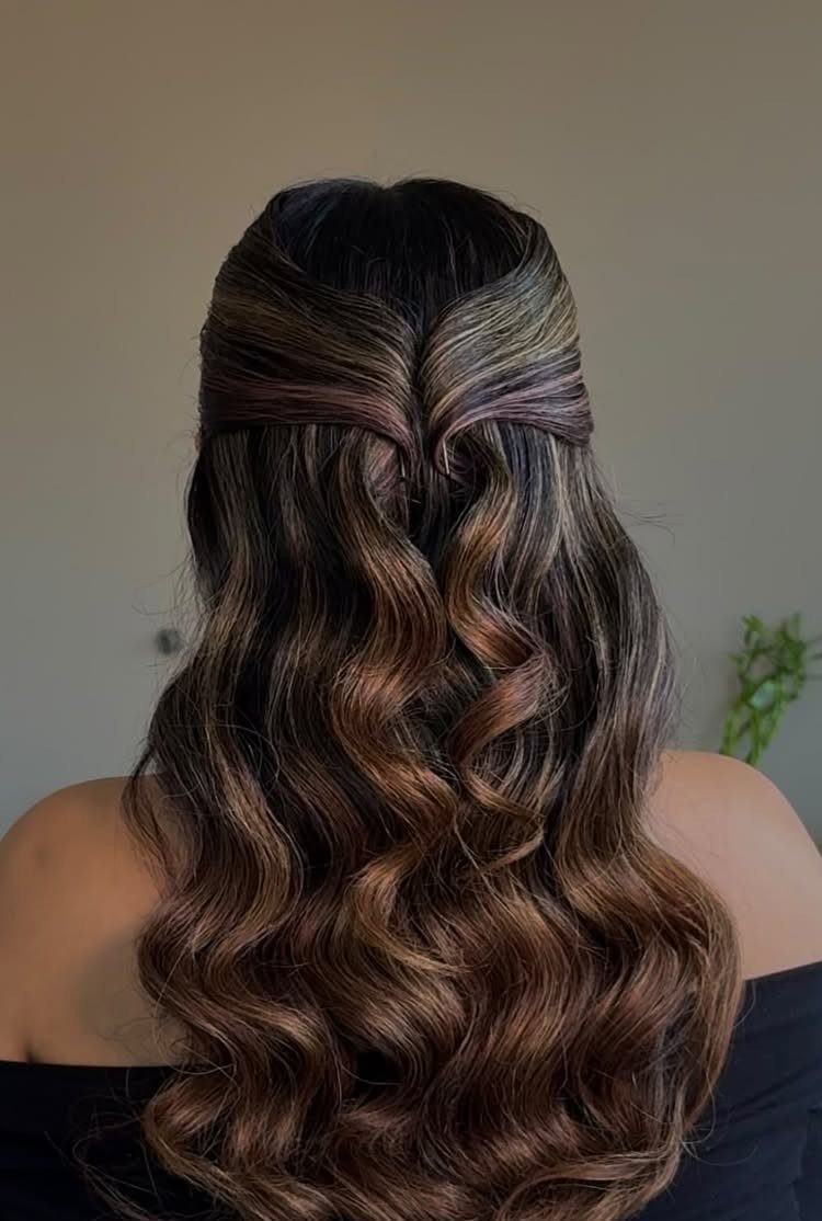 Long brown hair styled in a half-updo with voluminous, glossy curls from behind.