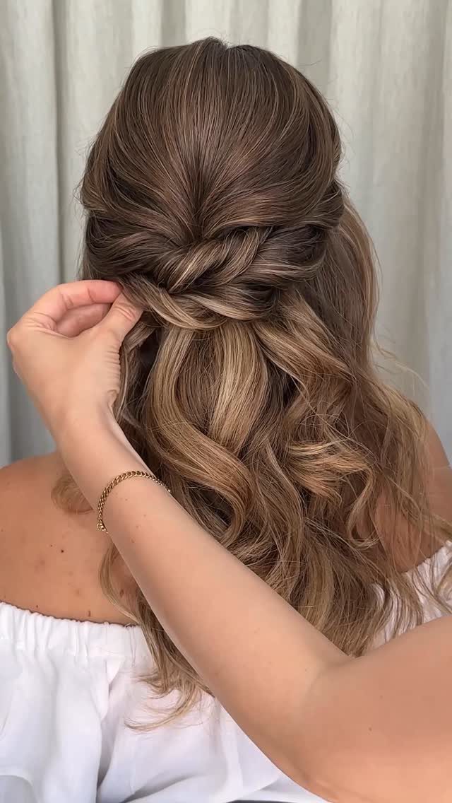 Long wavy brown hair styled in a half-updo with a twisted crown section.