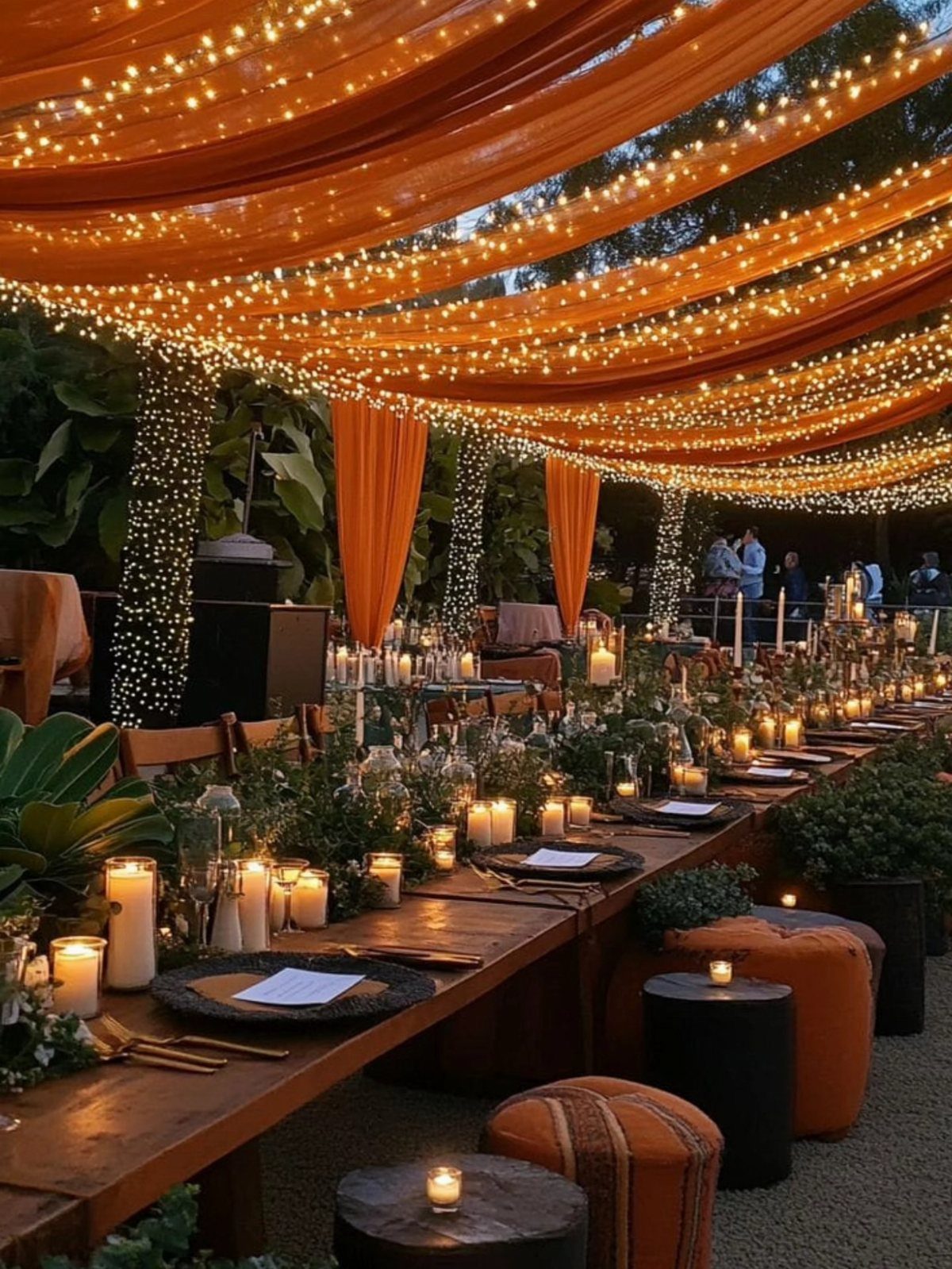 Orange fabric canopies with fairy lights draped over a long wooden wedding table