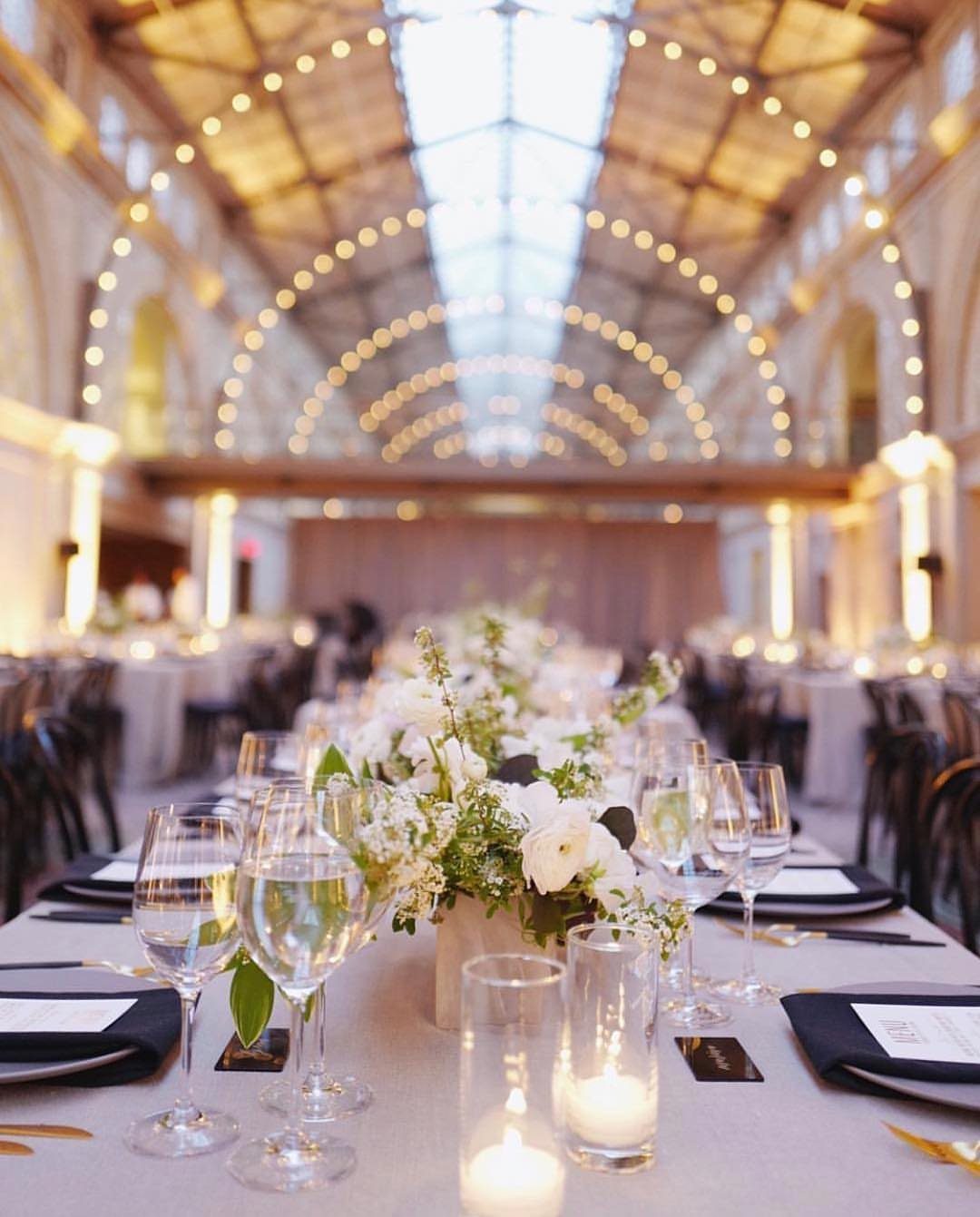 Grand hall with a vaulted skylight ceiling and fairy lights over a wedding table.