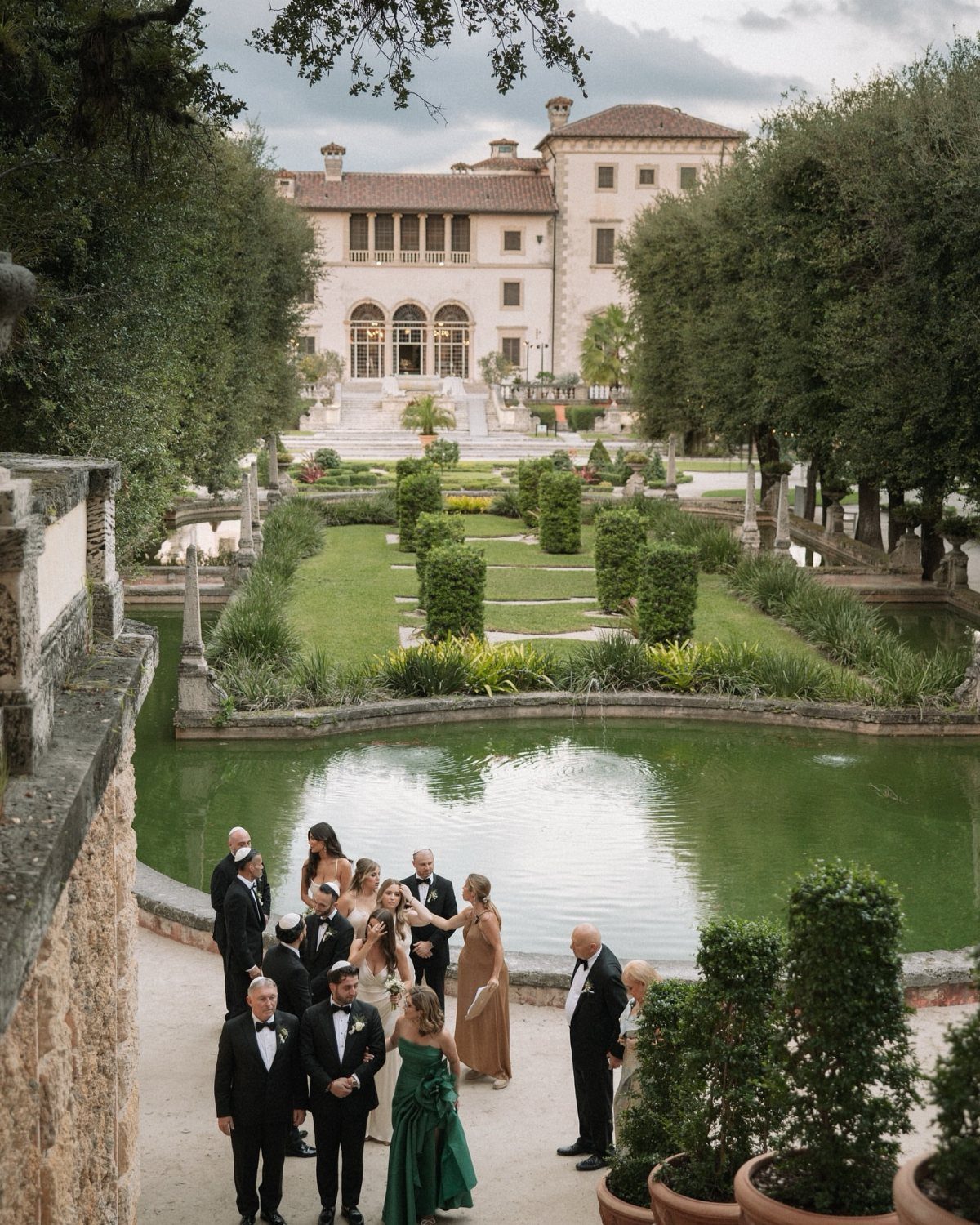 Historic Mediterranean estate with manicured gardens and a pond during a wedding event.