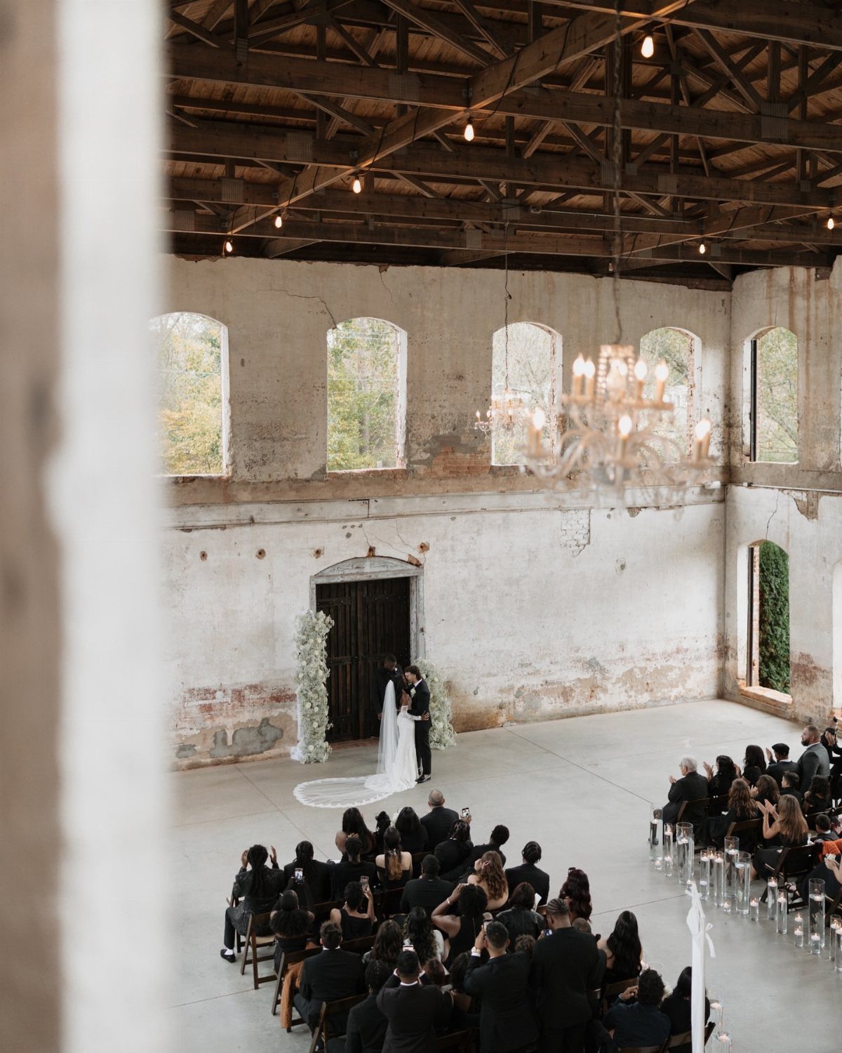 Wedding ceremony in a rustic historic mill with high ceilings and white walls.