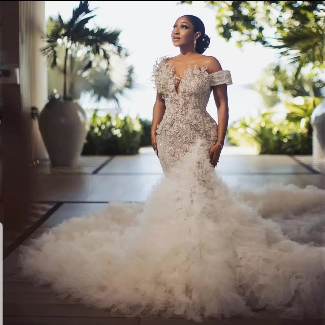 Woman in a fitted ivory hourglass mermaid wedding dress with a voluminous ruffled skirt.