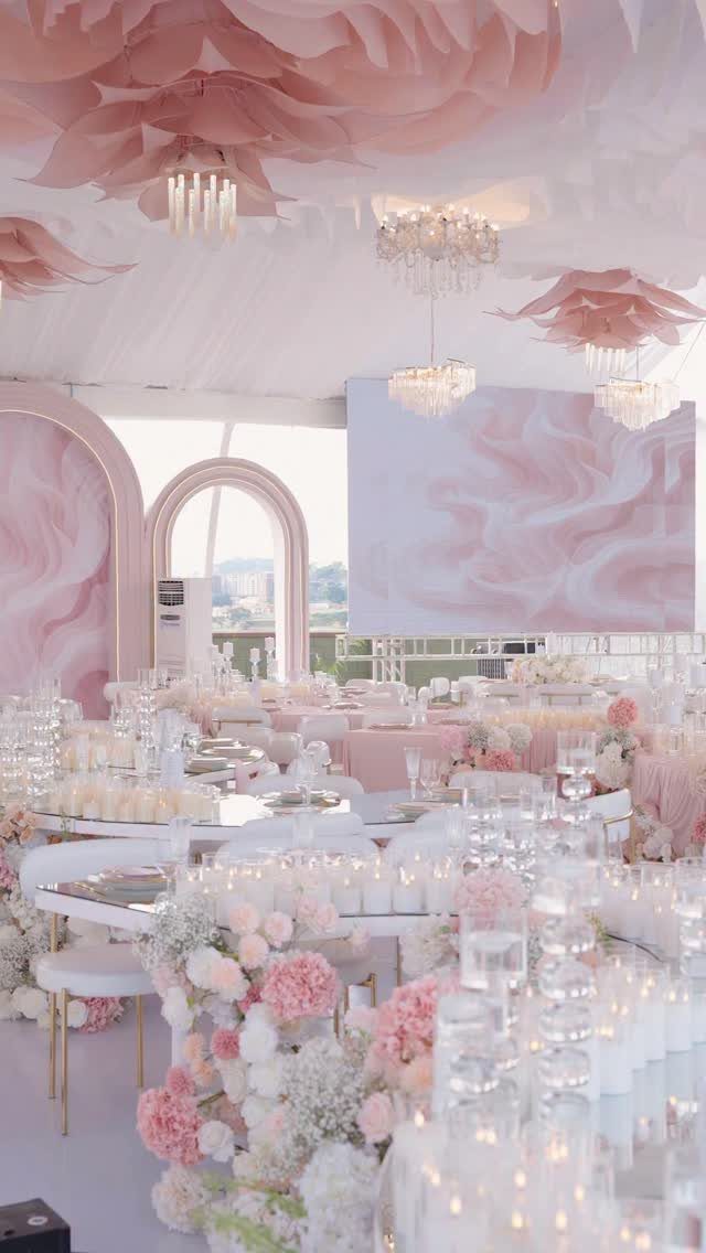 Light pink wedding table decor with floral arrangements and crystal chandeliers in a tent
