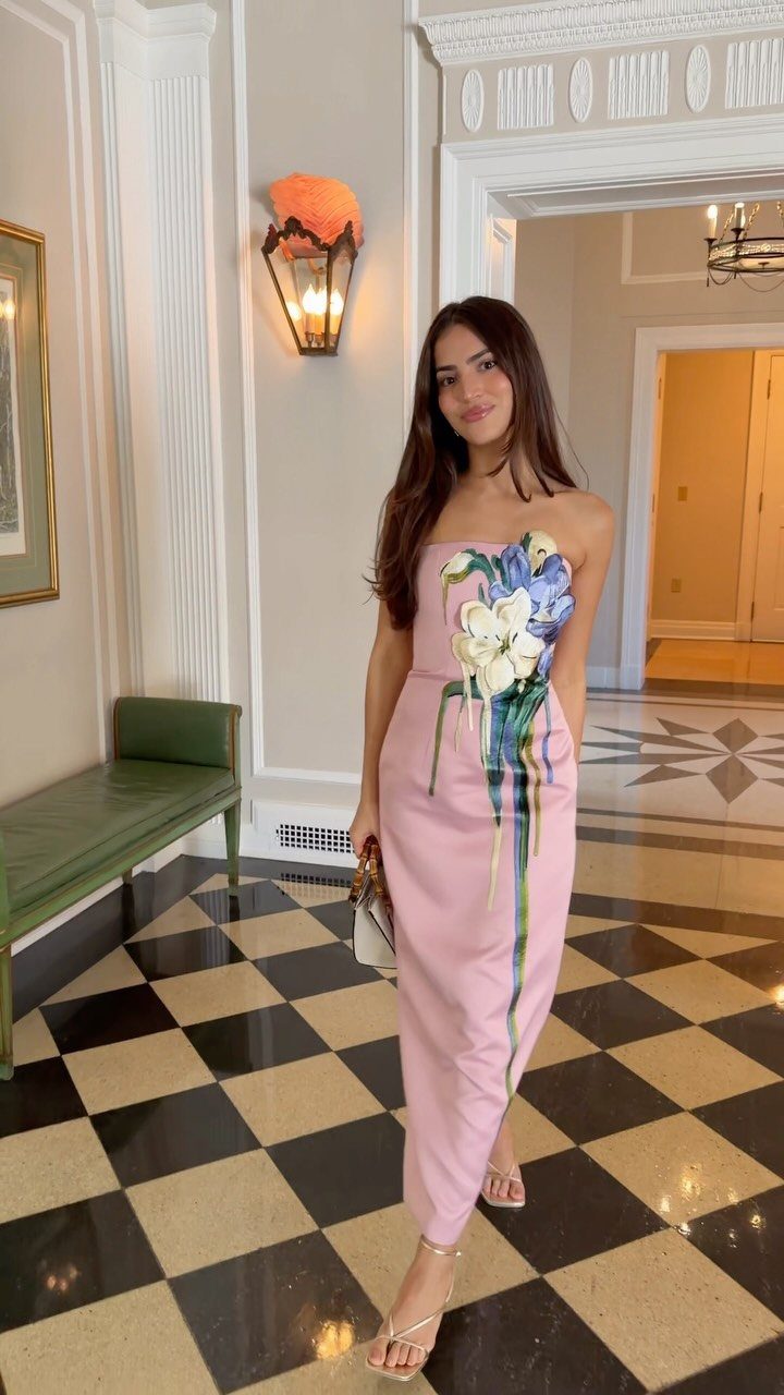 Woman wearing a strapless light pink floral midi dress on a checkered floor.