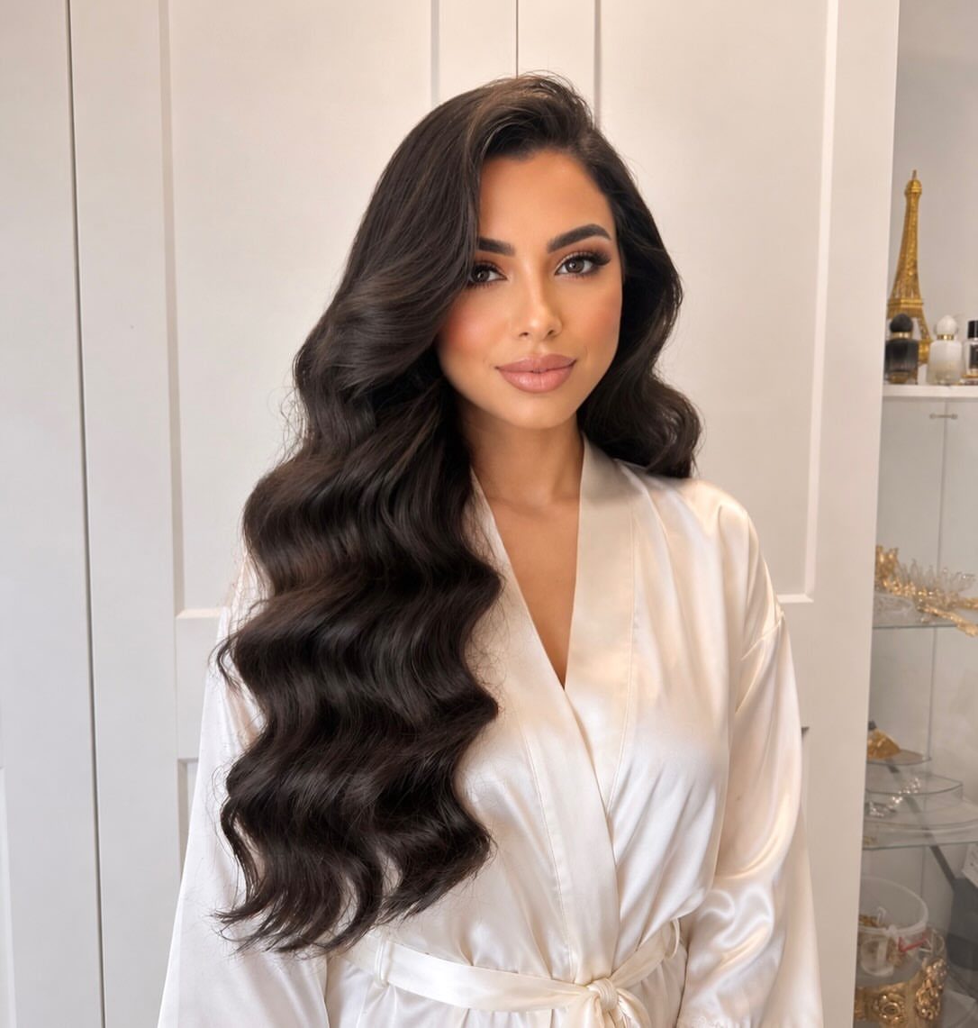 15 Long Hair Wedding Styles for Braids, Buns and Waves 5 Woman with long dark hair styled in voluminous polished waves wearing white satin robe