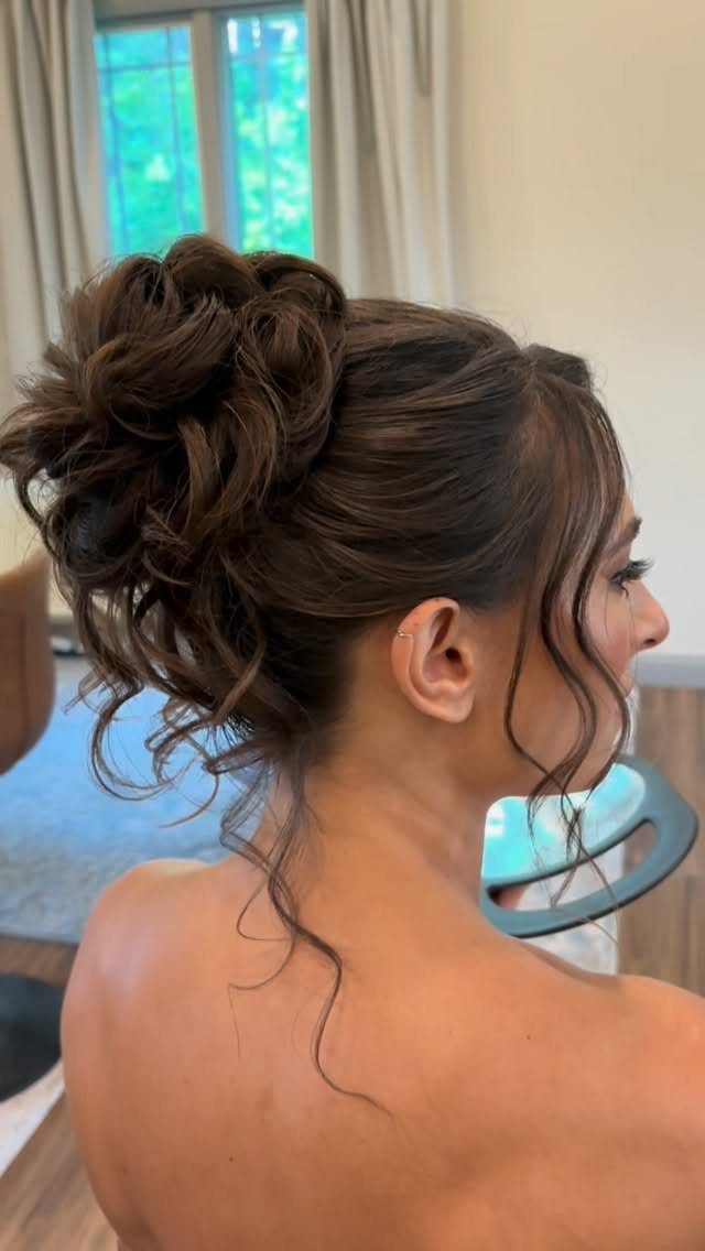 15 Long Hair Wedding Styles for Braids, Buns and Waves 11 Woman with brown hair in a curly high bun wedding hairstyle.