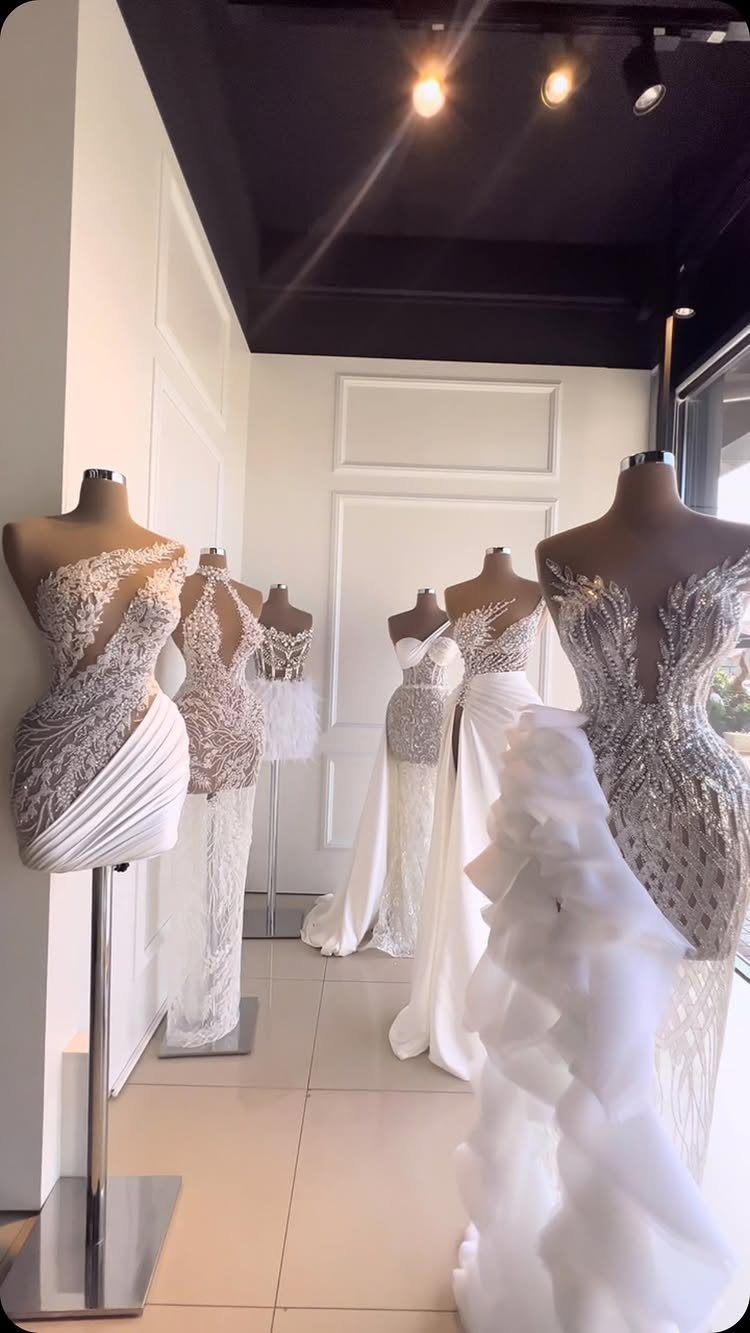 White lace wedding dresses on mannequins inside a bright bridal boutique showroom.