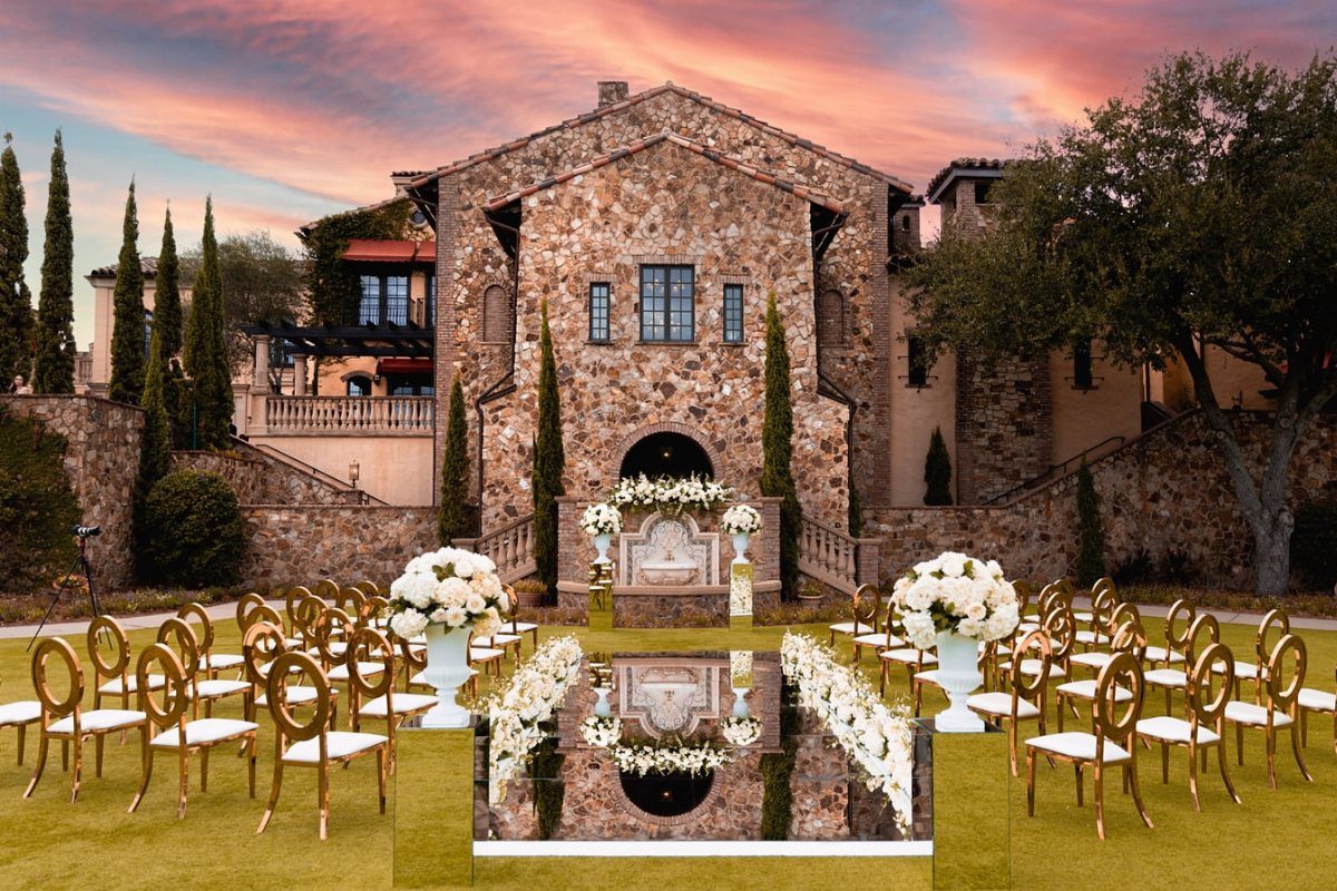 Outdoor wedding ceremony setup with gold chairs and reflective pool before a stone villa.