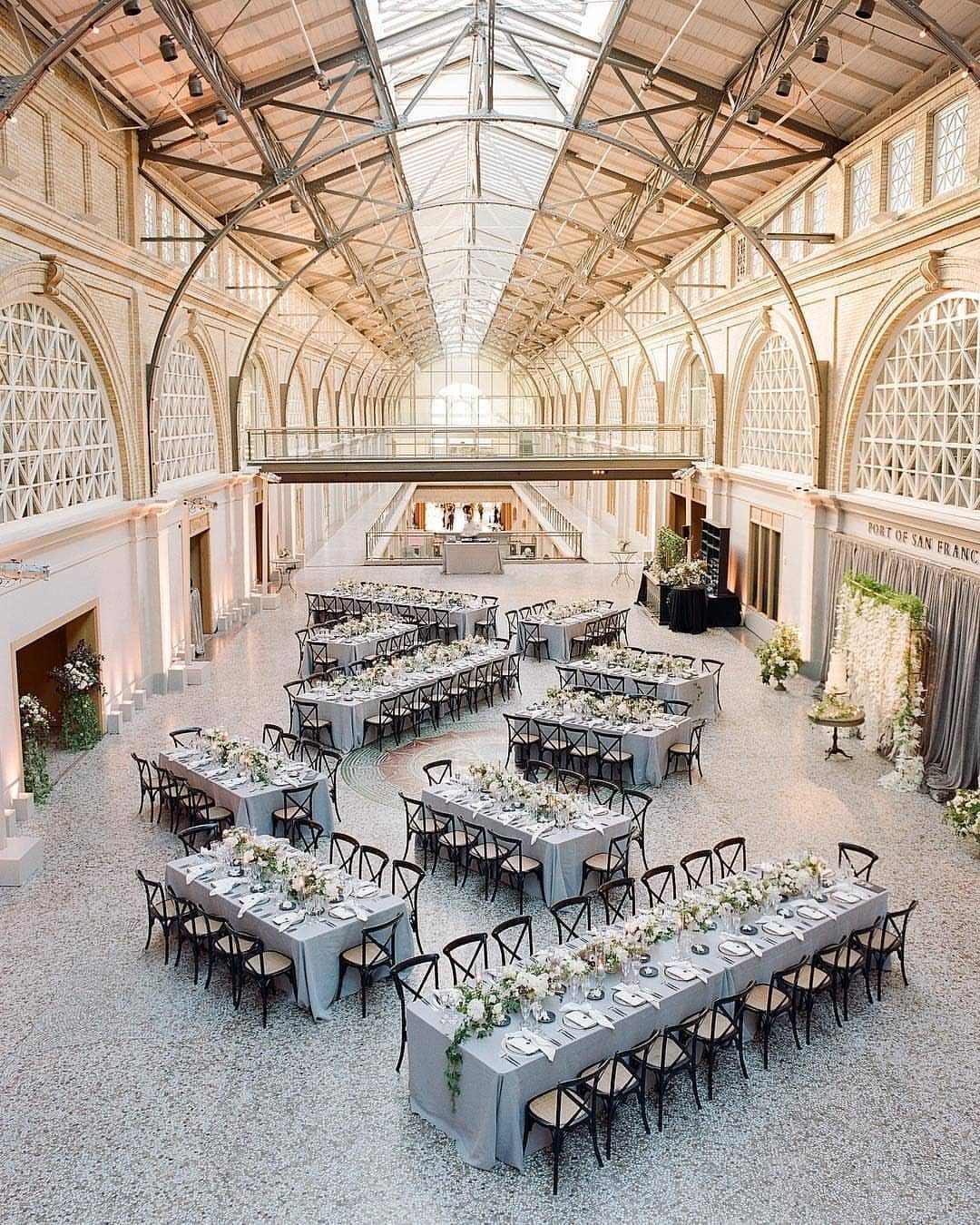 Grand historic hall with vaulted glass ceiling and long wedding reception tables.