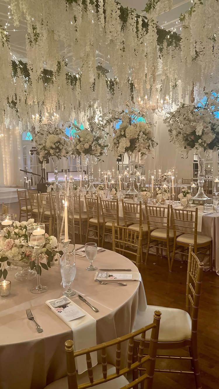 Wedding reception with gold chairs and white floral installations hanging from the ceiling.