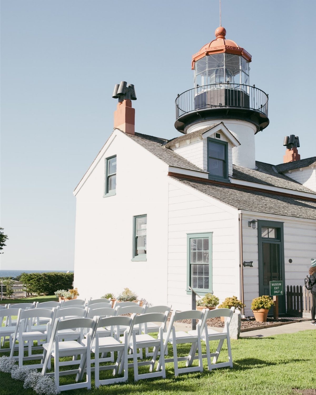 White lighthouse building with rows of white folding chairs for a wedding ceremony.