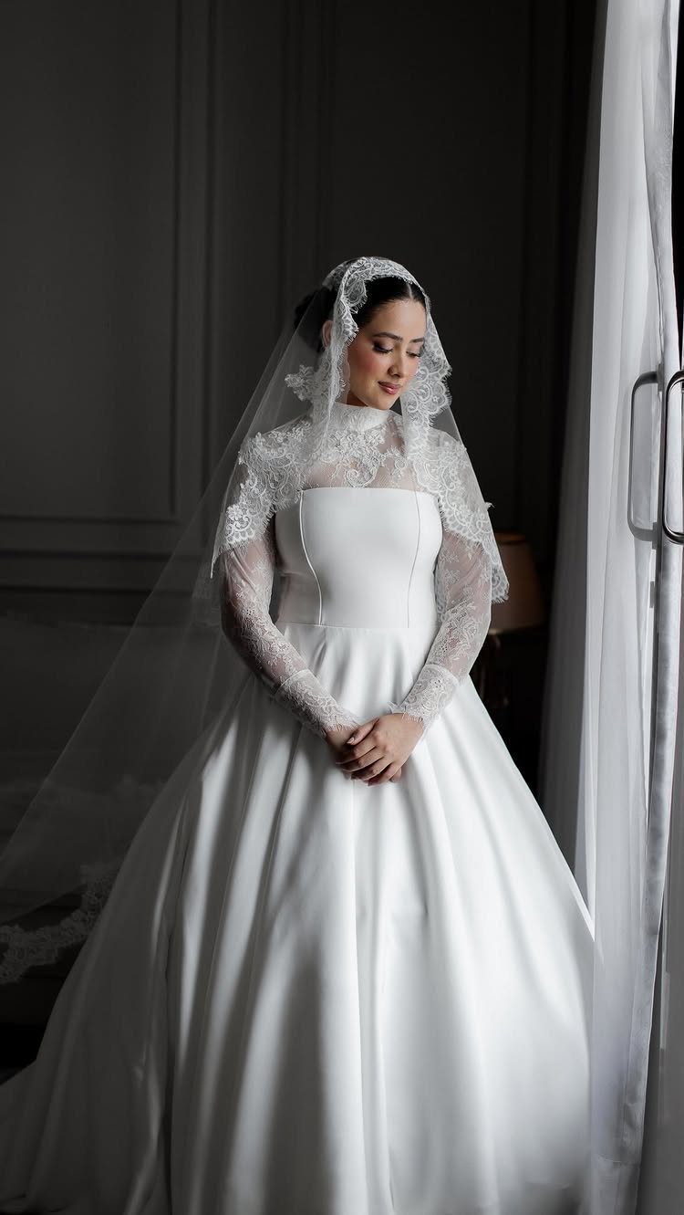 Bride in a white wedding dress wearing a lace mantilla veil over her head.