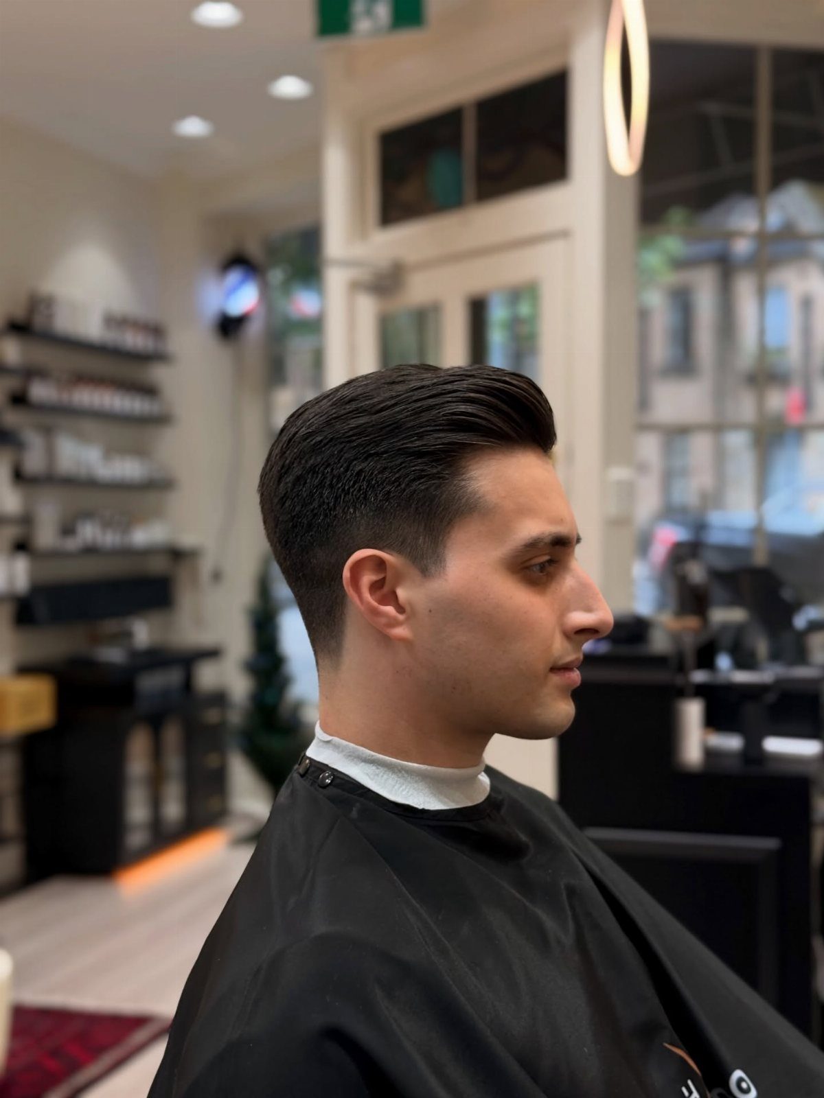 Man with a classic fade haircut and styled top in a barbershop.