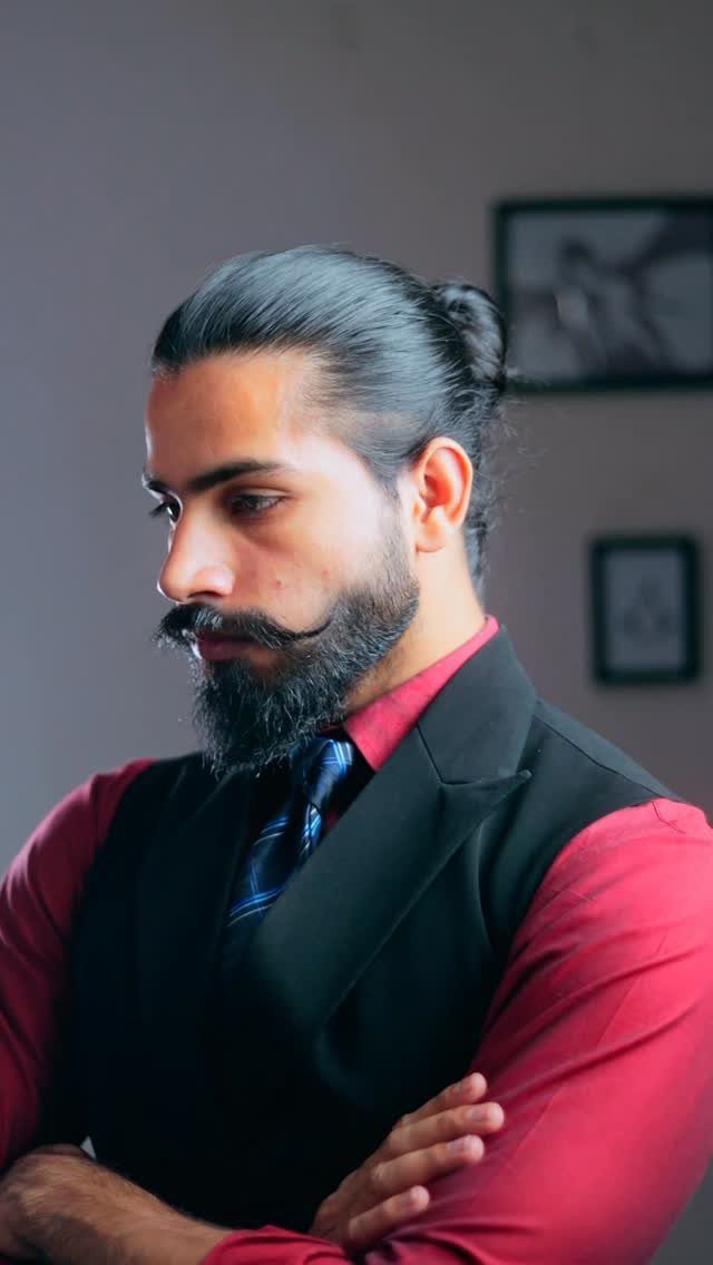Man with a beard and man bun wearing a red shirt and black vest