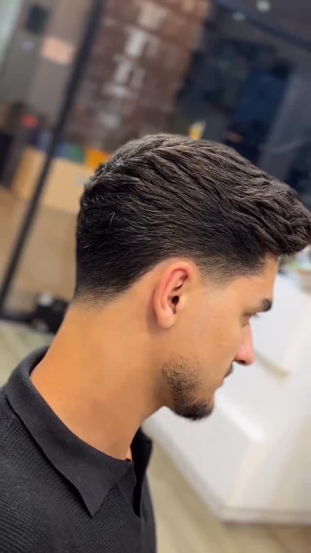 Man with a professional skin fade haircut and styled top in profile view.