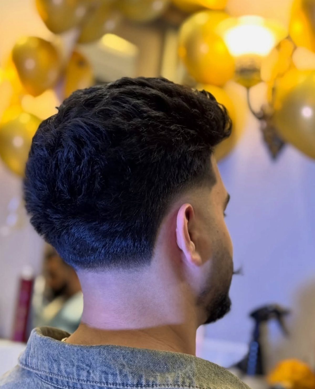 Man with a dark wavy pompadour hairstyle and a clean side fade.