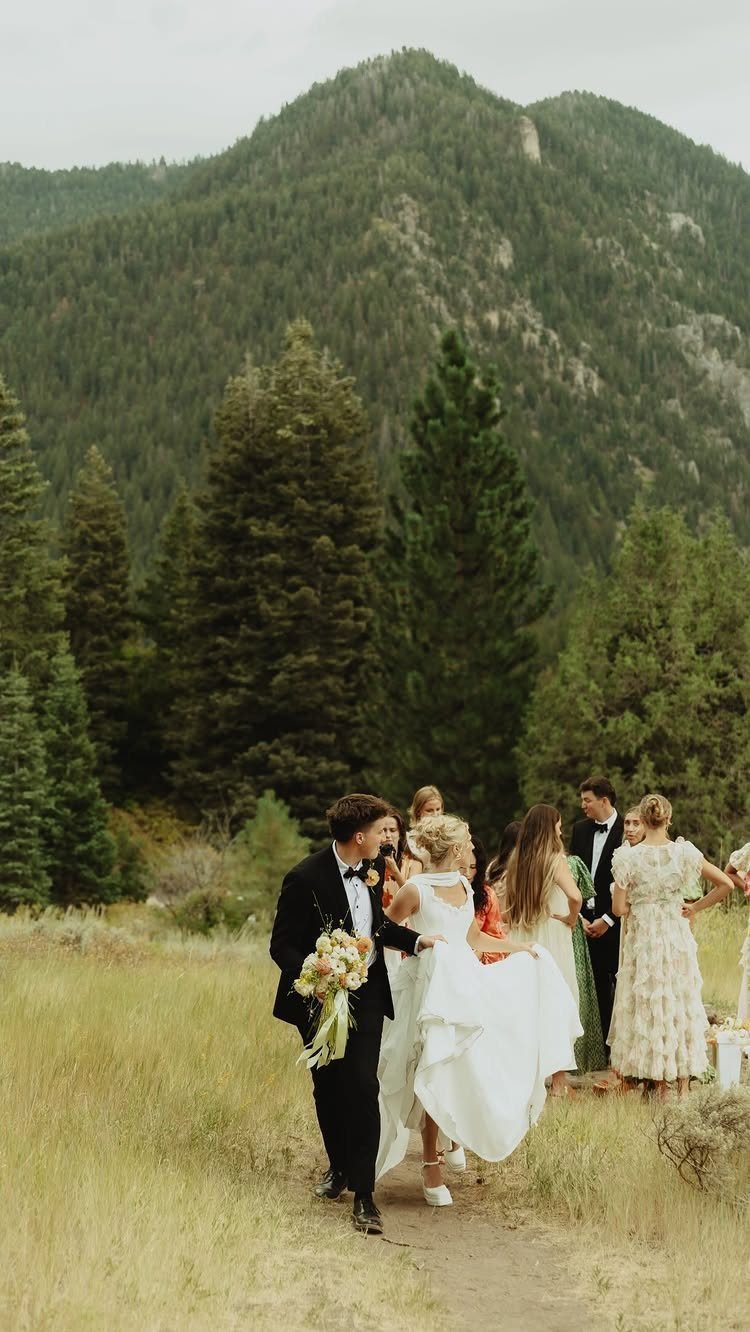 Bride and groom walking with their wedding party through a mountain meadow.