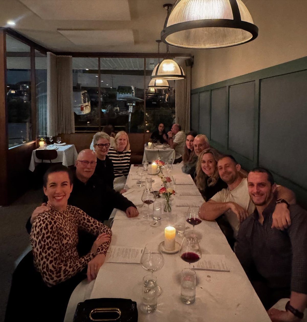 No Wedding Party? 6 Ideas for Celebrating Without One 4 Group of friends smiling while sitting around a long dinner table in a restaurant