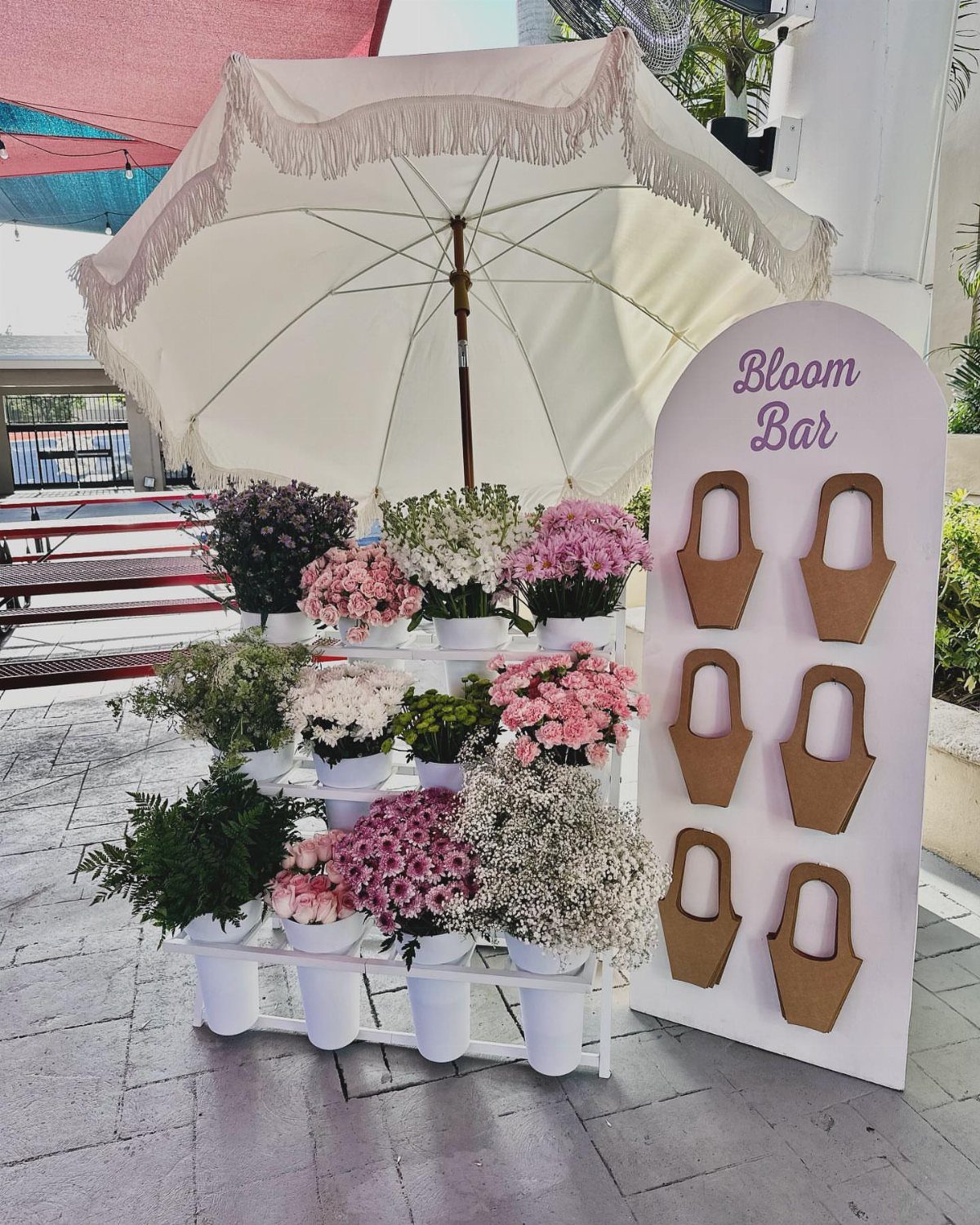 Bloom Bar with pink and white flowers in pots under a white umbrella