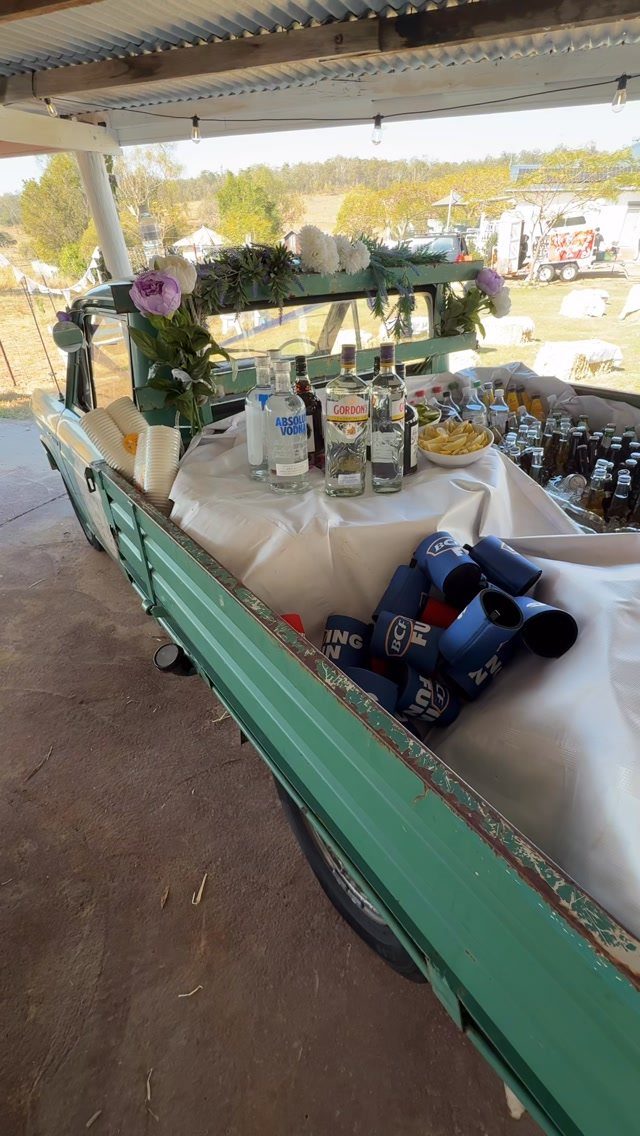 Green vintage truck bed serving as a self-serve drink station with liquor and beer.