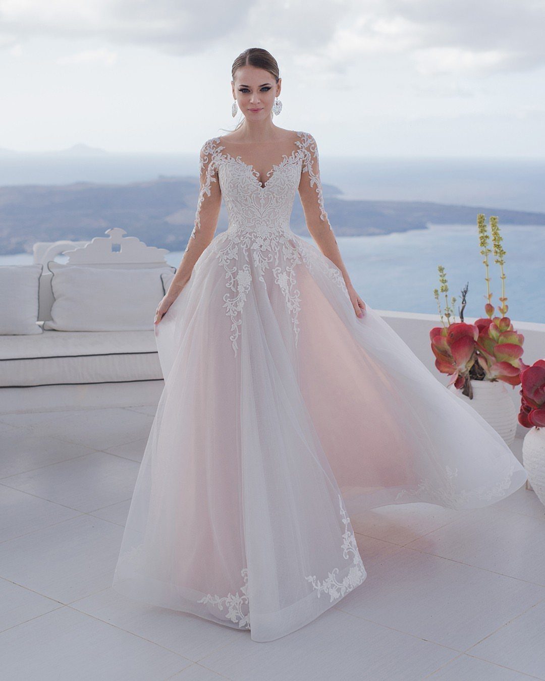 Woman in a dusty rose and white lace wedding dress on a coastal terrace.