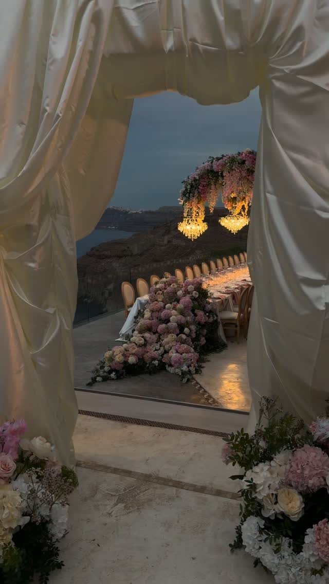 Outdoor wedding reception table with pink floral arrangements and hanging crystal chandeliers