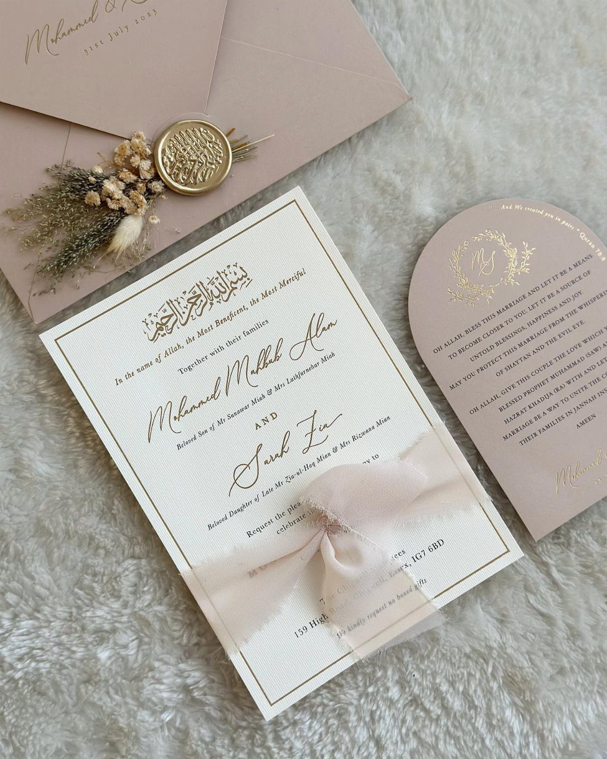 Wedding invitation set with white and blush pink cards, gold text, and wax seal.