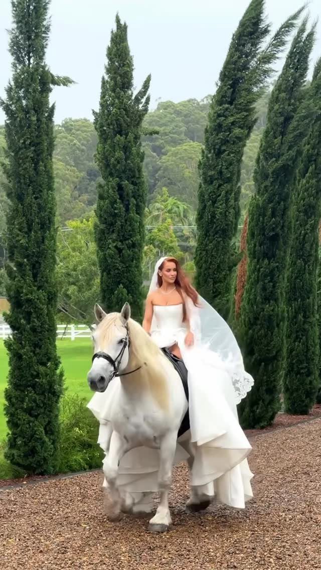 12 Pre Wedding Photoshoot Outfit Ideas for Couples 9 Woman in white wedding gown and veil riding a white horse among cypress trees.