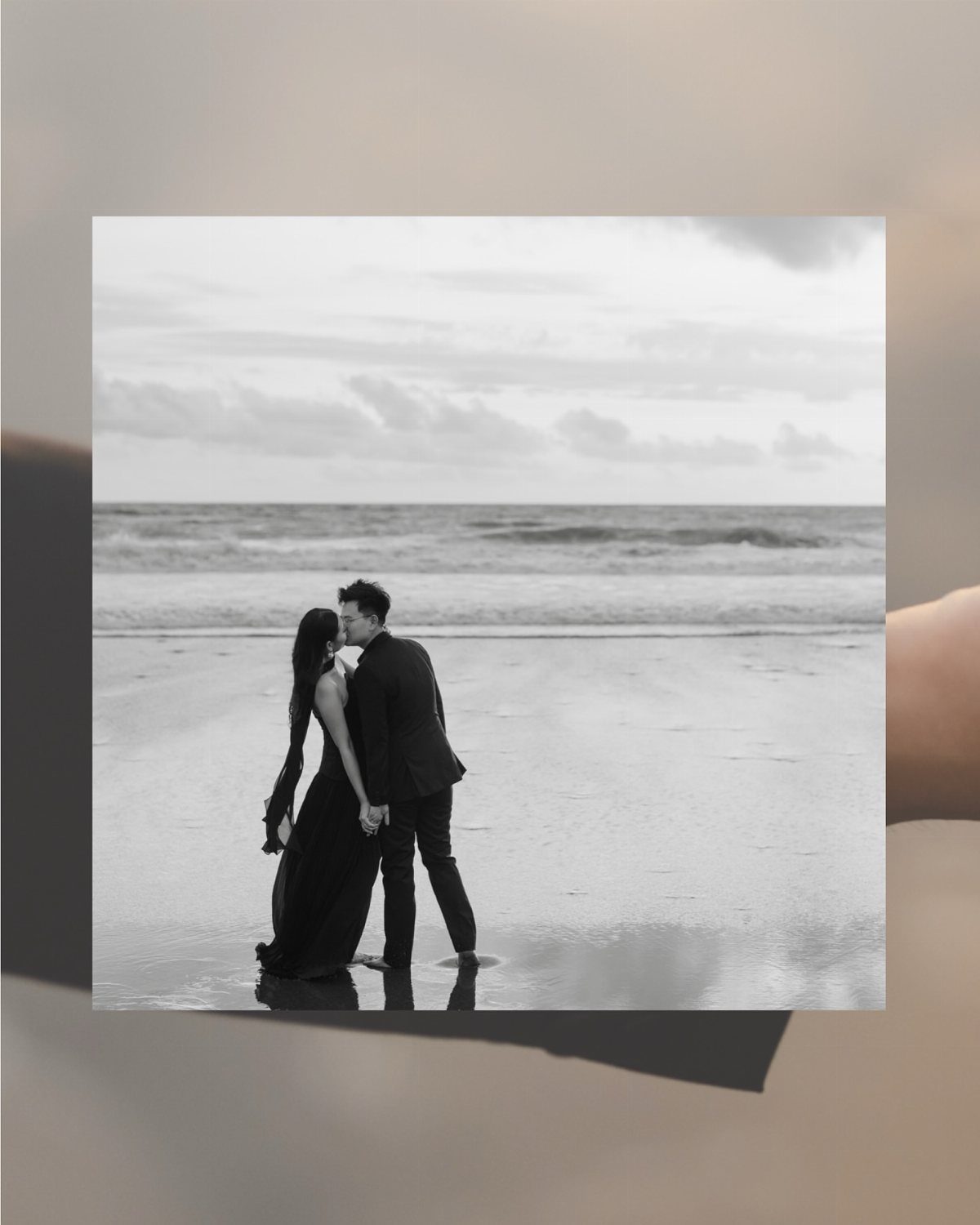 12 Pre Wedding Photoshoot Outfit Ideas for Couples 11 Couple in black formal attire holding hands on a beach in monochrome.
