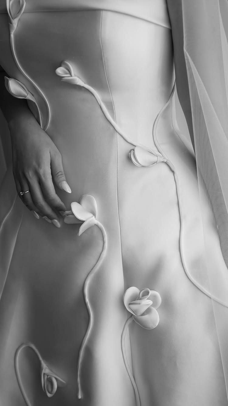 White wedding dress with 3D floral appliques and elegant curved piping details.