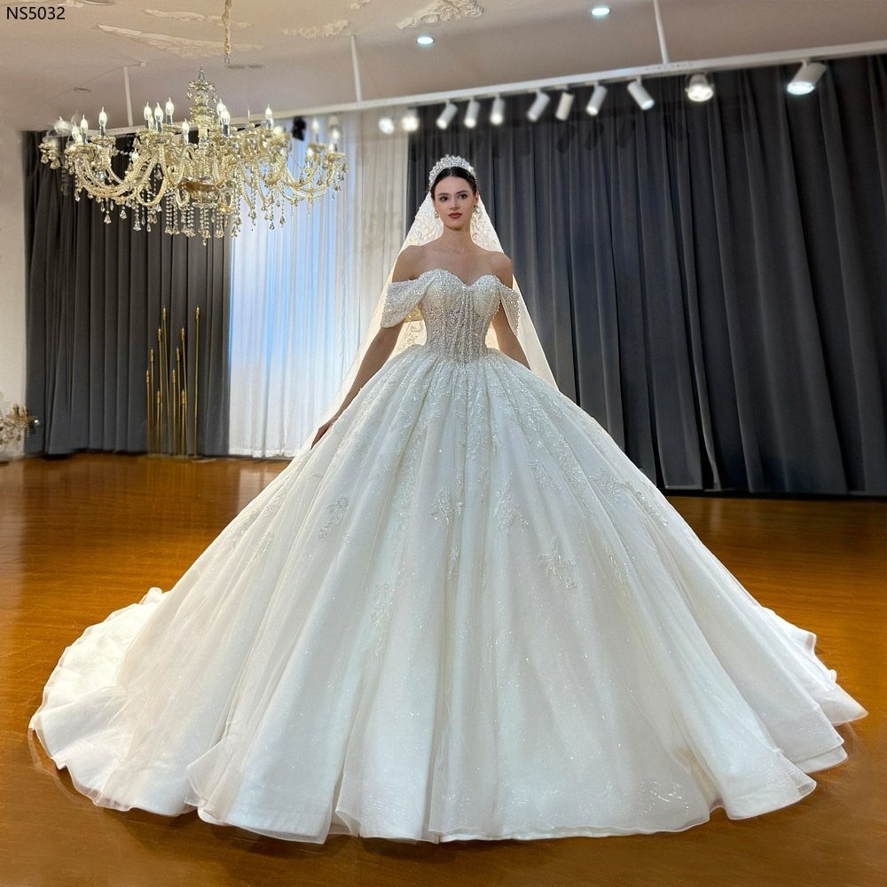 Woman in a voluminous white ball gown wedding dress with a tiara and veil.