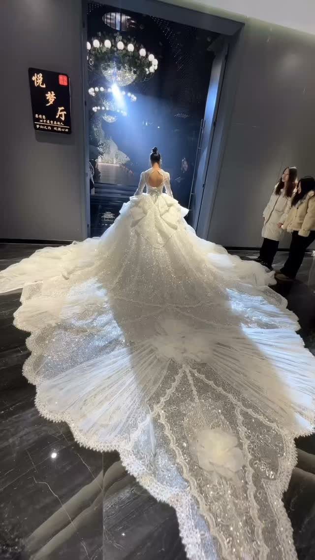 Woman wearing a white wedding dress with a massive, ornate lace train.