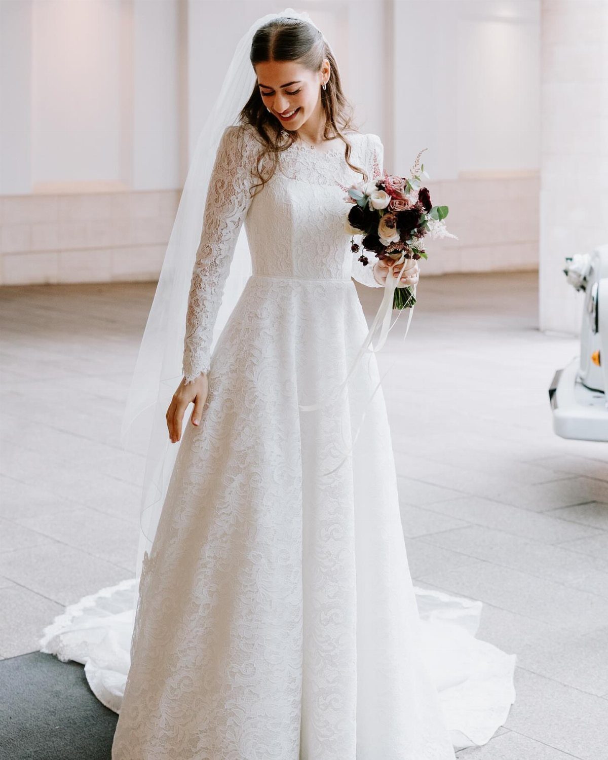 Bride in a white lace A-line wedding dress holding a floral bouquet
