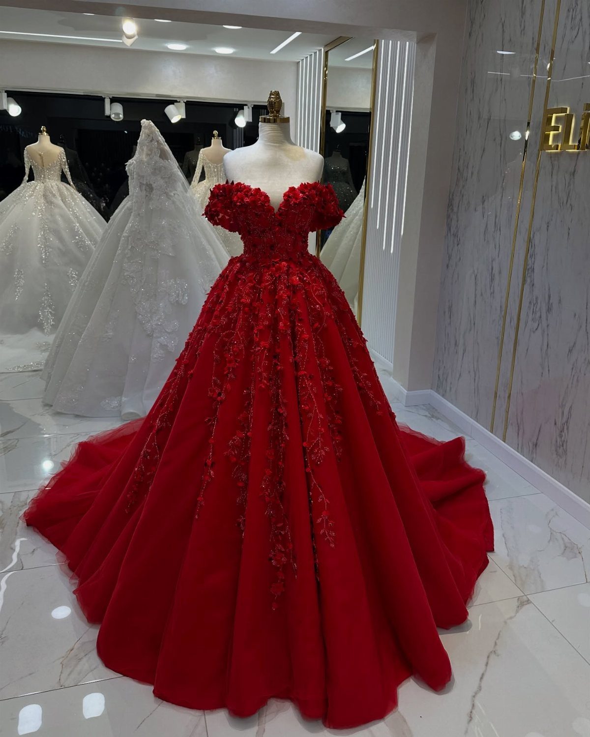10 Red Wedding Dresses for Brides Who Want Color 1 Bright red strapless ballgown wedding dress with floral embroidery on a white mannequin.