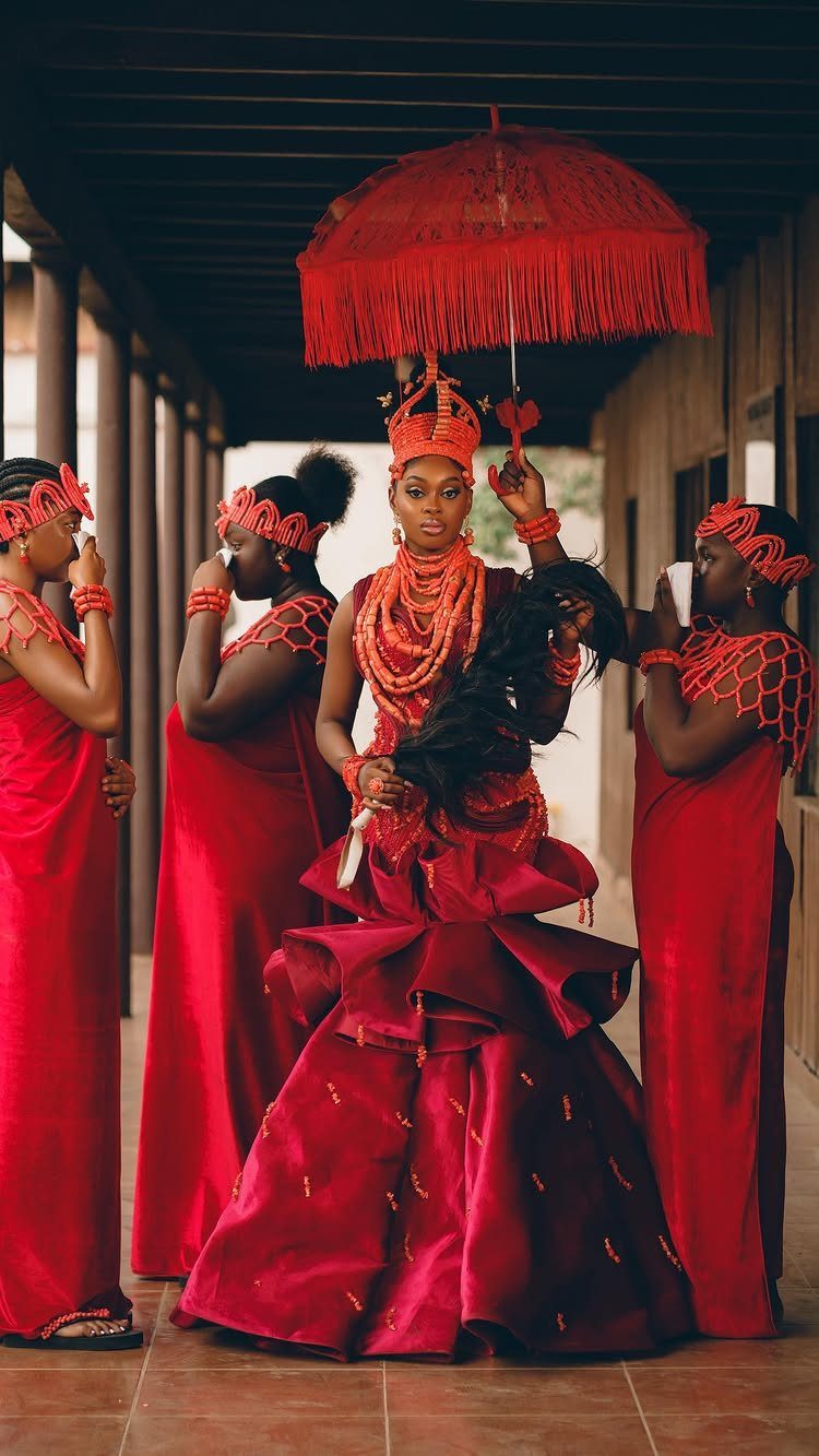 10 Red Wedding Dresses for Brides Who Want Color 10 Woman in a voluminous red bridal gown and coral beads holding a red umbrella.