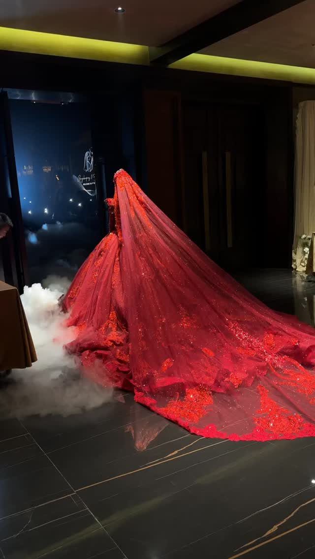 10 Red Wedding Dresses for Brides Who Want Color 7 Red wedding dress with a long lace train and white fog on floor.