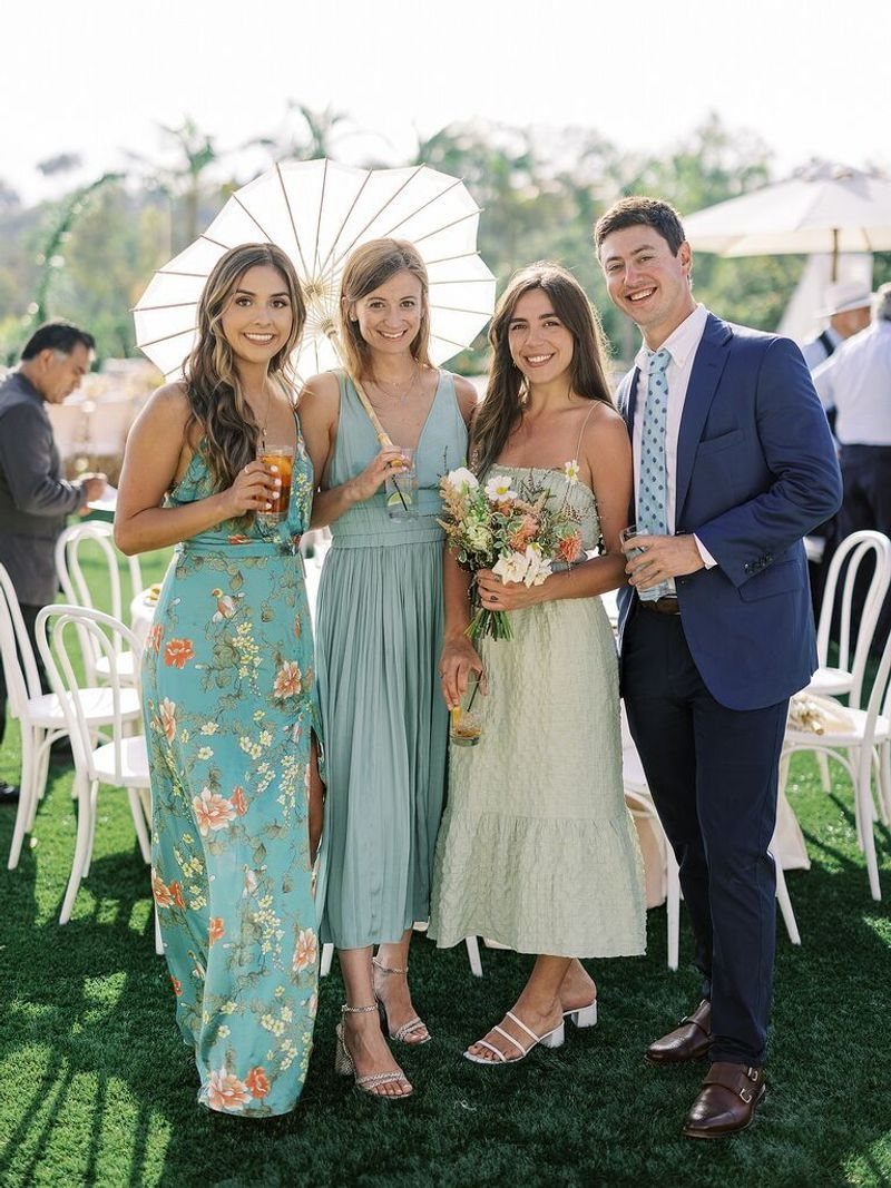Four wedding guests posing outdoors in semi-formal attire including colorful dresses and a navy suit.