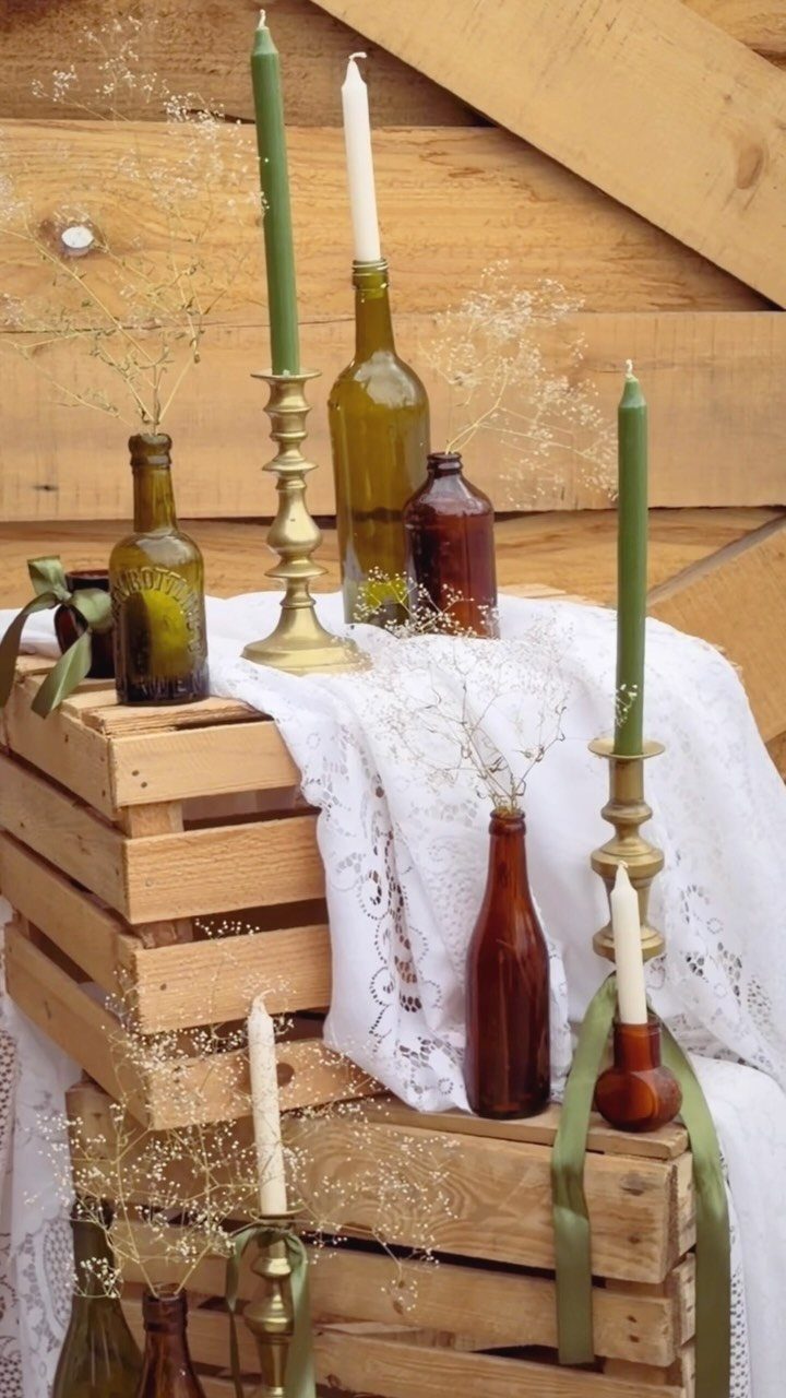 Amber glass bottles with baby's breath and taper candles on rustic wooden crates.
