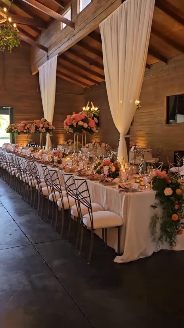 Gold metal chairs with white cushions at a rustic wedding banquet table.