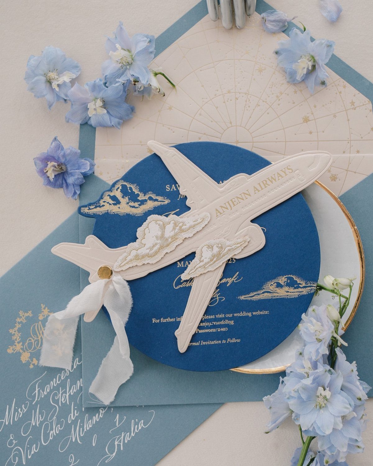 Save the Date Wedding Invite Ideas: 11 Styles to Try 10 Blue circular save the date card with a white airplane cutout and blue flowers.