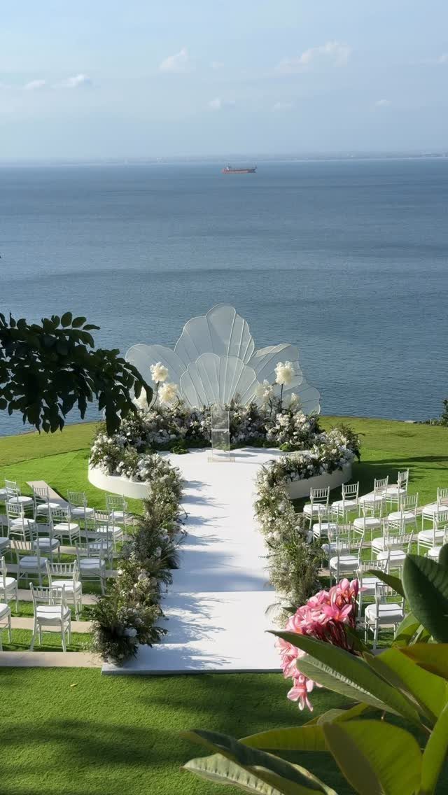 Outdoor wedding ceremony setup with white aisle and floral altar overlooking the ocean.